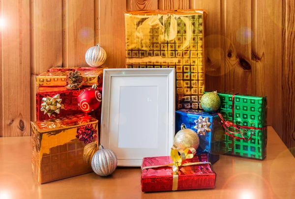 Biała ramka i Boże Narodzenie prezenty na drewnianym stole. — Zdjęcie stockowe