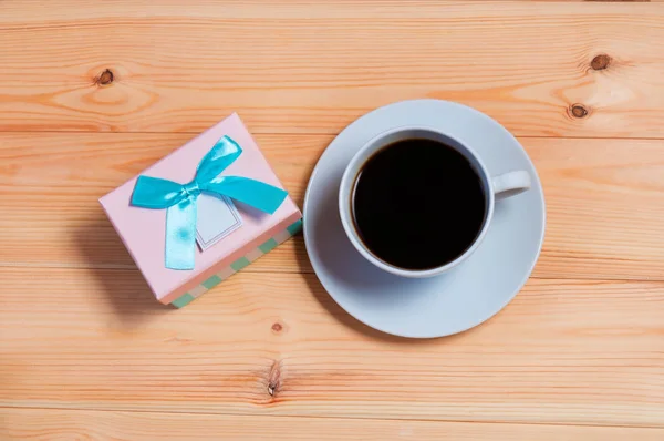 Чашка кофе и подарочная коробка на деревянном фоне — стоковое фото