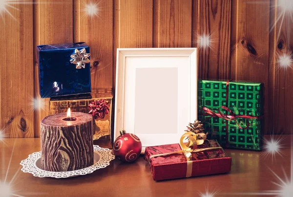 Witte foto frame, kaars en kerst cadeaus op houten tafel. — Stockfoto