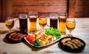 Bira ve ahşap masa üzerinde ızgara sosis gözlük 