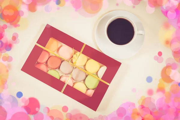 Kleurrijke bitterkoekjes in geschenk doos en wit kopje koffie — Stockfoto