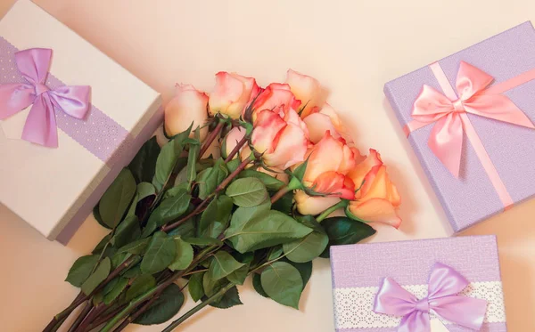 Hediye veya mevcut kutuları ve yukarıdan bej renkli arka plan üzerinde çiçekler