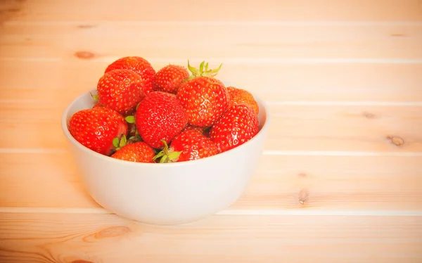 Ώριμες φράουλες κόκκινο σε λευκό μπολ στο ξύλινο τραπέζι. Επιλεκτική εστίαση. — Φωτογραφία Αρχείου