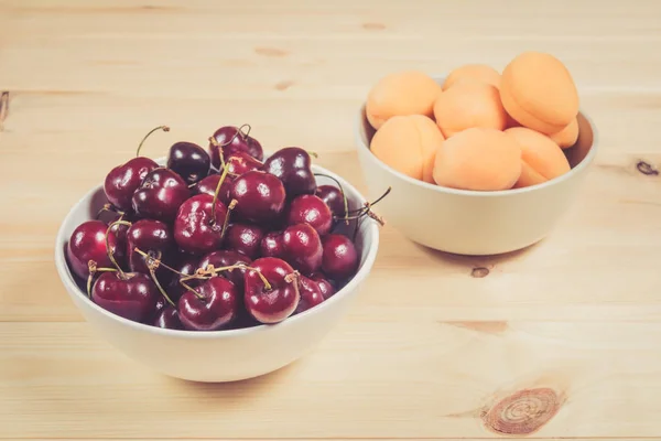 Чаши, полные свежих ягод вишни и абрикосов — стоковое фото