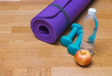 Yoga mat, halter, elma ve şişe suyu ahşap zemin üzerinde