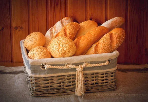 Свежий пшеничный хлеб в корзине на деревянном фоне — стоковое фото