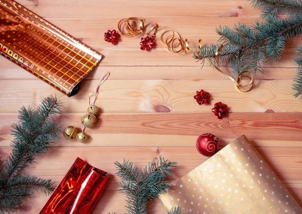 Julbakgrund med gran grenar, omslagspapper rullar och dekorationer på trä. Förberedelser inför semestern. — Stockfoto