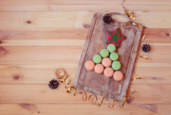 Forma de árbol de Navidad de coloridas galletas de macarrones y galletas de jengibre en forma de estrella en la mesa de madera . —  Fotos de Stock