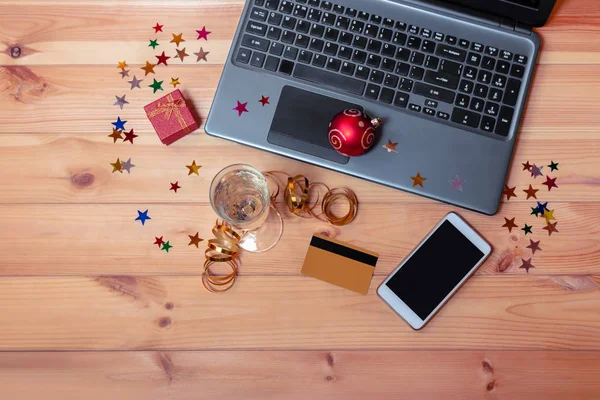 Bilgisayarlı, akıllı, kredi kartlı, bir bardak şampanyalı ve hediye kutulu Noel işyeri. Noel alışveriş konsepti. 