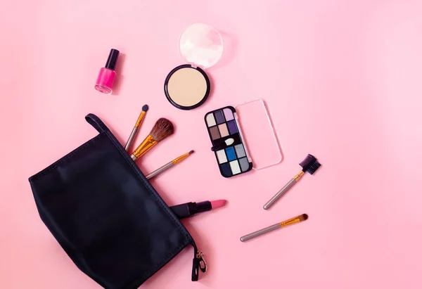 Borsa per il trucco con prodotti cosmetici di bellezza e pennelli per il trucco su sfondo rosa . — Foto Stock