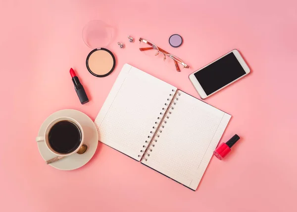 Σημειωματάριο, φλιτζάνι καφέ, γυαλιά, καλλυντικά μακιγιάζ, smartphone, βερνίκι νυχιών και σκουλαρίκια σε ροζ φόντο. — Φωτογραφία Αρχείου