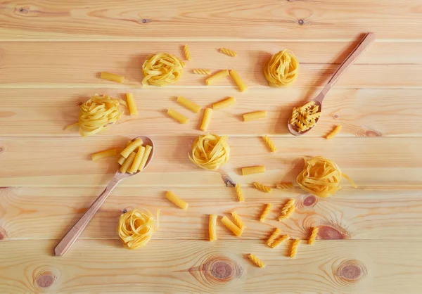 Lebensmittelmuster aus verschiedenen Arten roher Pasta auf Holzgrund. — Stockfoto