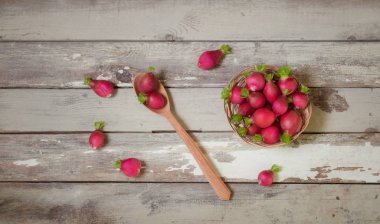 Tahta kaşıkta taze turp ve eski ahşap masada hasır sepette..