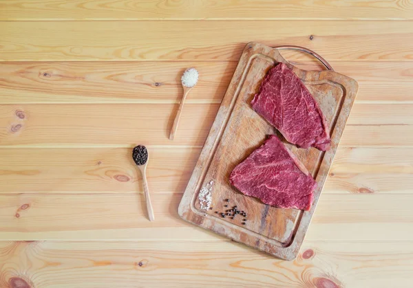 Сырое свежее мраморное мясо Черный Ангус стейки на резке доски и приправы рядом. Деревянный фон . — стоковое фото