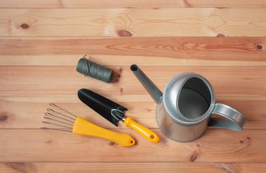 Su kovası ve ahşap masada sarı bahçe aletleri. Kopyalama alanı olan üst görünüm.