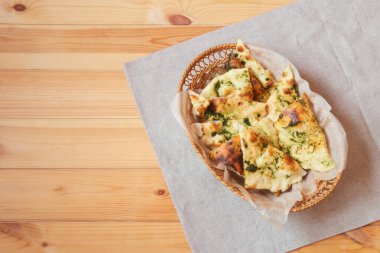 Tahta masadaki sepette aromatik pesto soslu buğday Focaccia ekmeği. Kopyalama alanı olan üst görünüm.