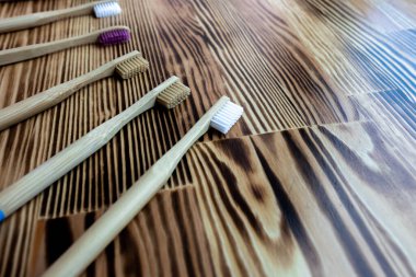 Birçok renkli bambu diş fırçası ahşap bir arka planda yatar. Çevre dostu. Doku. mesaj için yer. Tıkının. Tüylerin yakın plan görüntüsü