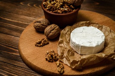 Ahşap arka planda ceviz çekirdekli Camembert veya Brie peyniri. Uzayı kopyala Penicillium camemberti 'nin tepesinde beyaz küf büyüyor.. 