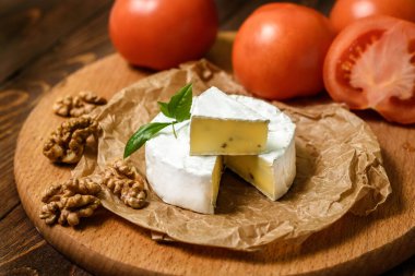 Ahşap arka planda ceviz çekirdekli Camembert veya Brie peyniri. Uzayı kopyala Penicillium camemberti 'nin tepesinde beyaz küf büyüyor.. 