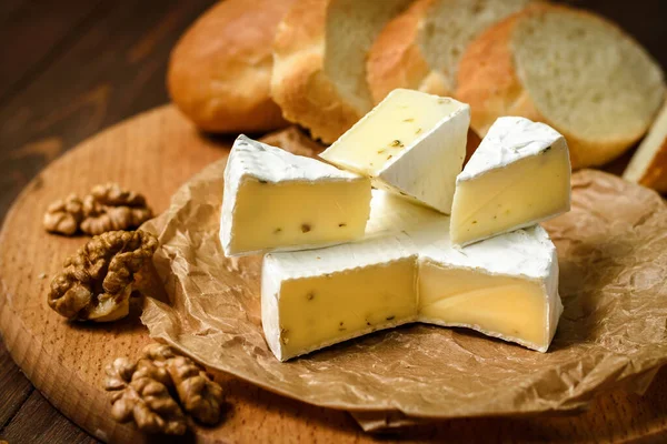 Ahşap arka planda ceviz çekirdekli Camembert veya Brie peyniri. Uzayı kopyala Penicillium camemberti 'nin tepesinde beyaz küf büyüyor.. 
