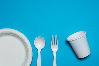 Tek kullanımlık kaşık, çatal, cam ve bir tabak mısır nişastası mavi arka planda. Biyo-çözünebilir çevre dostu yemekler. İzole et. Plastiğin modern biyomateryallerle değiştirilmesi.