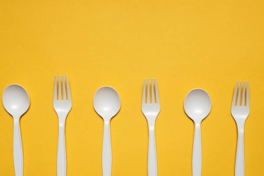 Sarı arka planda tek kullanımlık kaşık ve çatal mısır nişastası. Biyolojik çözünebilir çevre dostu piknik masaları. İzole et. Plastiğin modern biyomateryallerle değiştirilmesi.