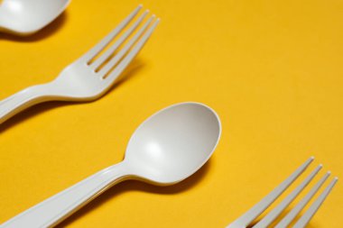 Sarı arka planda tek kullanımlık kaşık ve çatal mısır nişastası. Biyo-çözünebilir çevre dostu tek kullanımlık sofra takımı. İzole et. Plastiğin yerini modern biyomateryaller aldı. yakın plan
