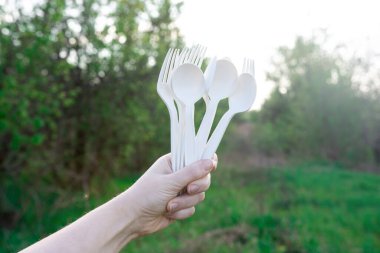 Doğanın arka planında, tek kullanımlık ayrıştırılabilir kaşık ve çatal mısır nişastası. Piknik için sofra takımı. Çevre dostu. Plastiği modern malzemelerle değiştirmek.