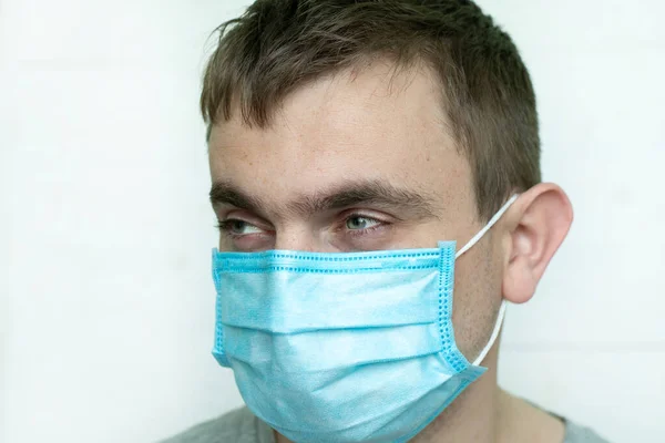 Man portrait in medical surgical mask on a white background. look to the side of the camera. place for text