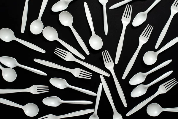 disposable biodegradable forks and spoons of corn starch on a black background. isolate. eco friendly. modern replacement for platen dishes.