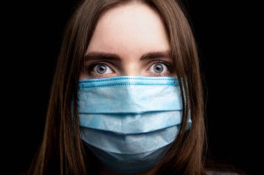 Siyah arka planda tıbbi maske takmış genç bir kızın yakın plan portresi. Hijyen konsepti. izole et