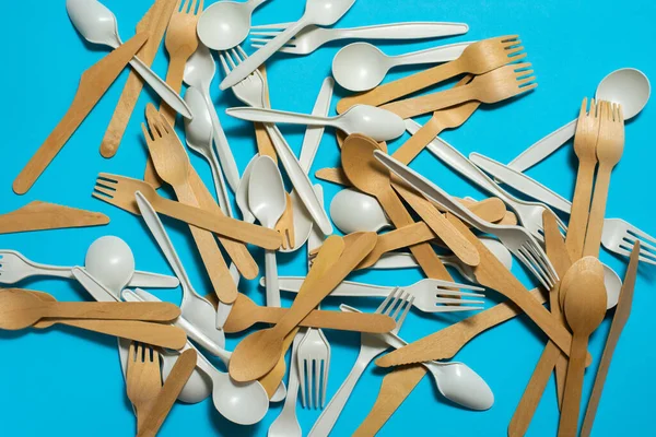 biodegradable disposable tableware on a blue background. spoons, forks, knives made of wood and corn starch. isolate. place for text. ecofriendly concept. modern replacement plastic