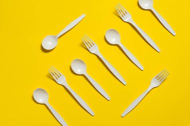 Biyo-çözünebilir, tek kullanımlık, sarı arka planı olan bir sofra takımı. Çatal ve kaşık dolusu mısır nişastası. İzole et. Plastiğin yerine modern bir şey. Biyomalzemeler. mesaj için yer. maket yap