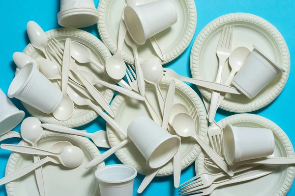 eco-friendly disposable tableware on a blue background. isolate. spoons, forks, plates, glasses of corn starch. biodegradable dishes. natural materials for replacing plastic.