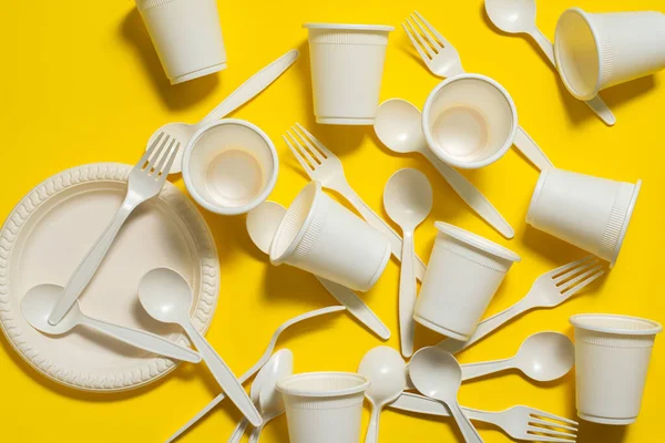 Many sets of biodegradable disposable tableware on a  yellow  background. Spoons, forks, plates, glasses of corn starch. eco friendly. modern environmental biomaterials replacement plastic.