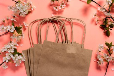 Kiraz çiçekleri çerçevesinde pembe arkaplan üzerinde el sanatları paketleri.