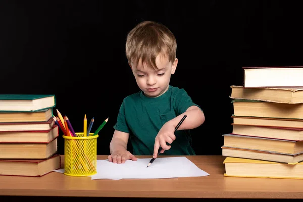 Rapaz Secretária Desenha Com Lápis Fundo Preto Pilhas Livros Estão — Fotografia de Stock