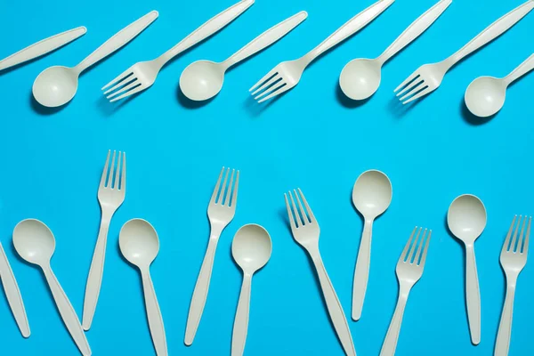 eco-friendly disposable tableware on a blue background. isolate. corn starch spoons and forks. biodegradable dishes. natural materials for replacing plastic. place for text