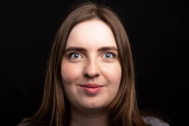 Siyah arka planda uzun sarı saçlı genç bir kızın portresi. Yakın plan. İzole et. Avrupa görünüşü. Gülümseyen bir kadın