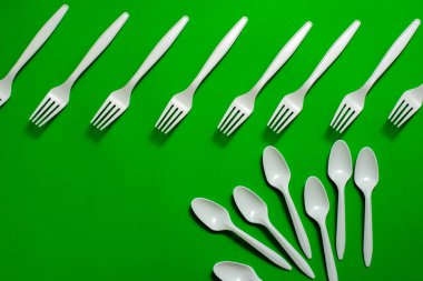 Yeşil arka planda çevre dostu tek kullanımlık sofra takımı. İzole et. Mısır nişastası kaşıkları ve çatallar. Biyo-çözünebilir yemekler. Plastik değiştirmek için doğal malzemeler. metin için yer