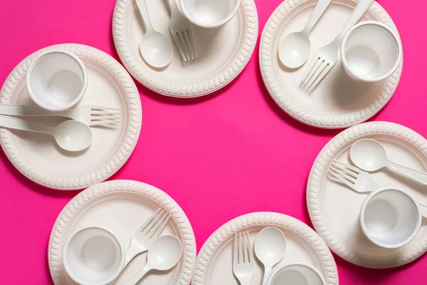 Pembe arka planda altı adet tek kullanımlık kaşık, çatal, tabak ve bir bardak mısır nişastası. Biyo-çözünebilir yemekler. Çevre dostu tecrit. Plastiğin modern biyomateryallerle değiştirilmesi