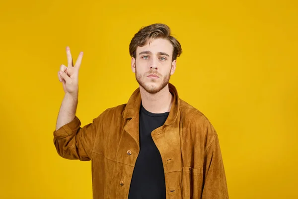 Sarı arka planda kameraya bakan yakışıklı bir adam.