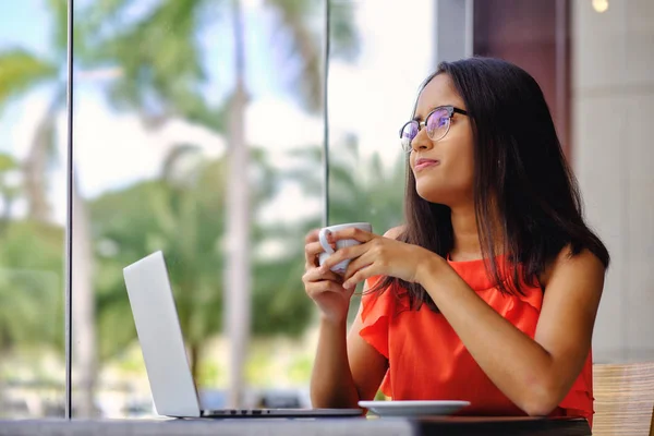 Young girl drinking coffee in front of laptop — Stock Photo, Image