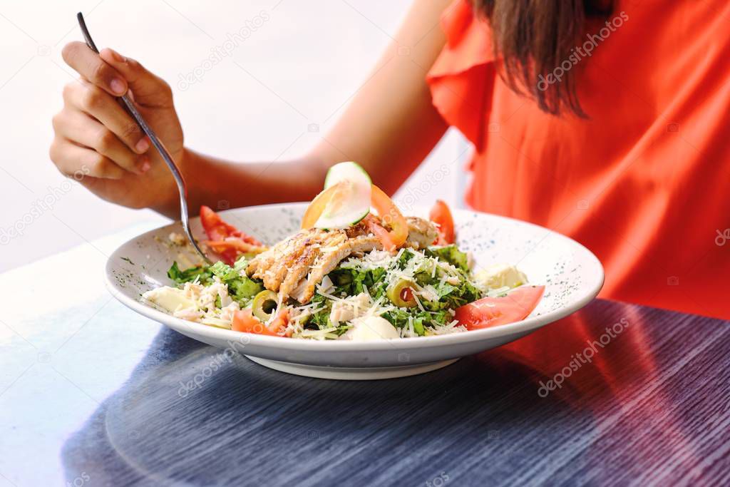 Closeup on cesar salad eated by a girl in cafe