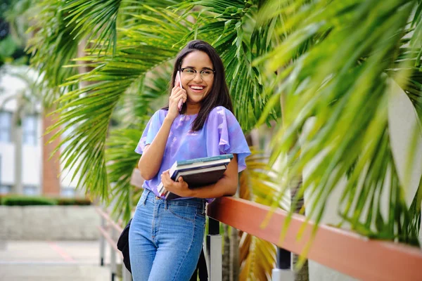 Üniversite kampüsü bahçesinde cep telefonuyla konuşan öğrenci kız.