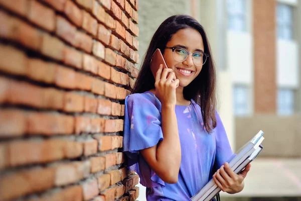 Üniversite kampüsü bahçesinde cep telefonuyla konuşan öğrenci kız.