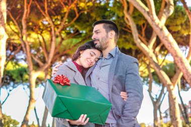 Genç çift parkta eğleniyor ve güzel doğanın tadını çıkarıyor. Yumuşak arka planda Akdeniz ağaçları - Sevgililer Günü derin duyguları ve aşk duyguları kavramı - sıcak renk görüntüsü