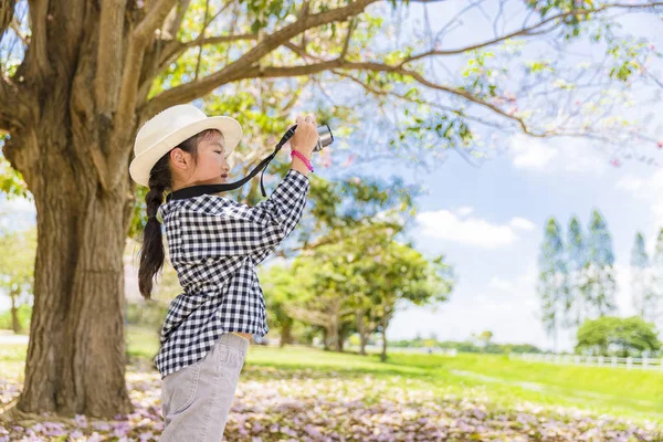 Asiatiska barn bär retro hatt tar fotografiet i den vackra rosa blomman på golvet — Stockfoto