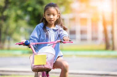 Asyalı küçük kız binicilik bisiklet park veya Bahçe, küçük g
