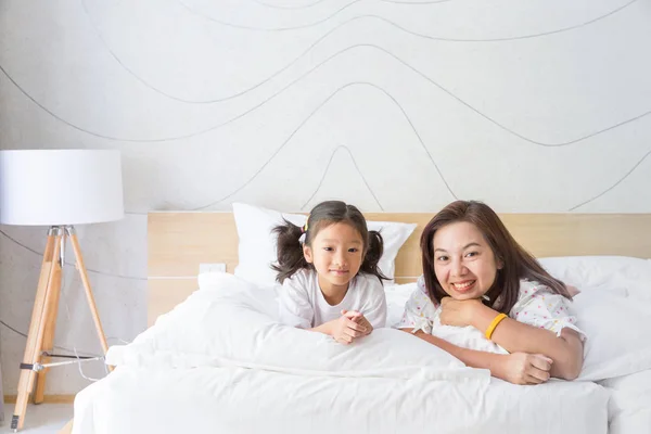 Glad asiatiska familjen mor och dotter leende på säng — Stockfoto